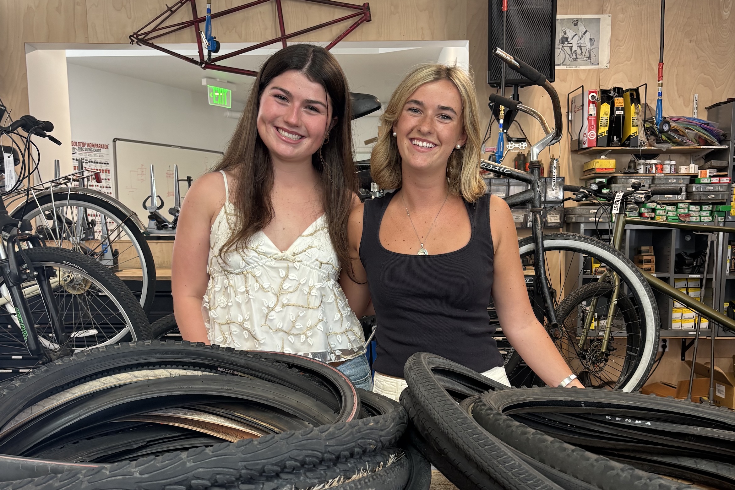 Students, Alexis and Virginia, in front of bike tires they are getting recycled