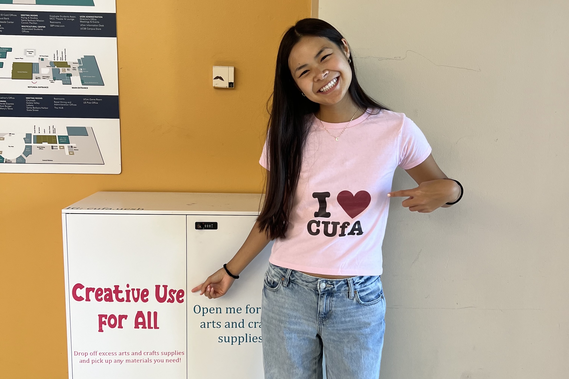 Student, Cacee, in front of her Creative Use for All station in the UCEN with a gift and take library of art supplies