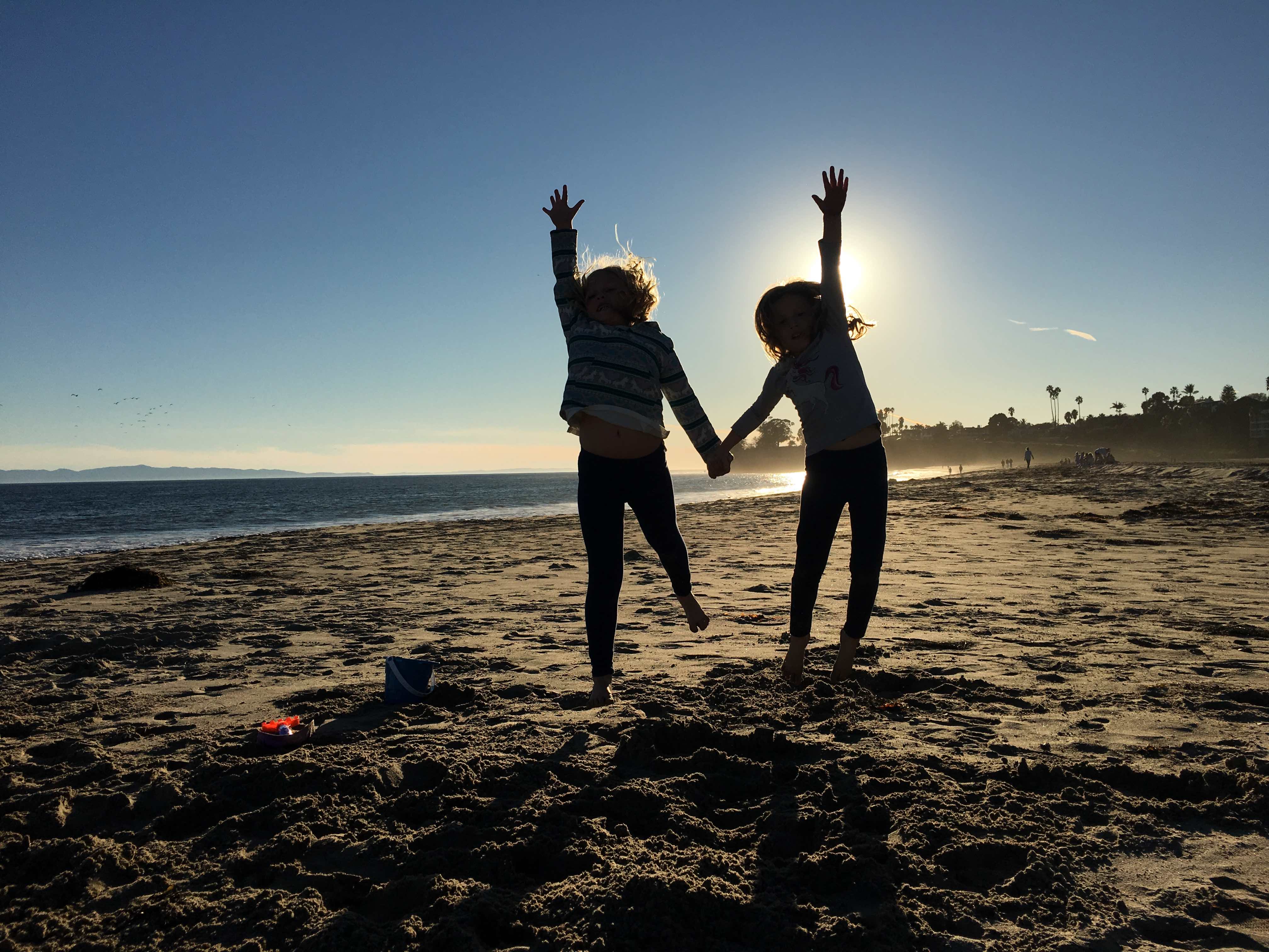 Two elementary students jumping for joy at the beach