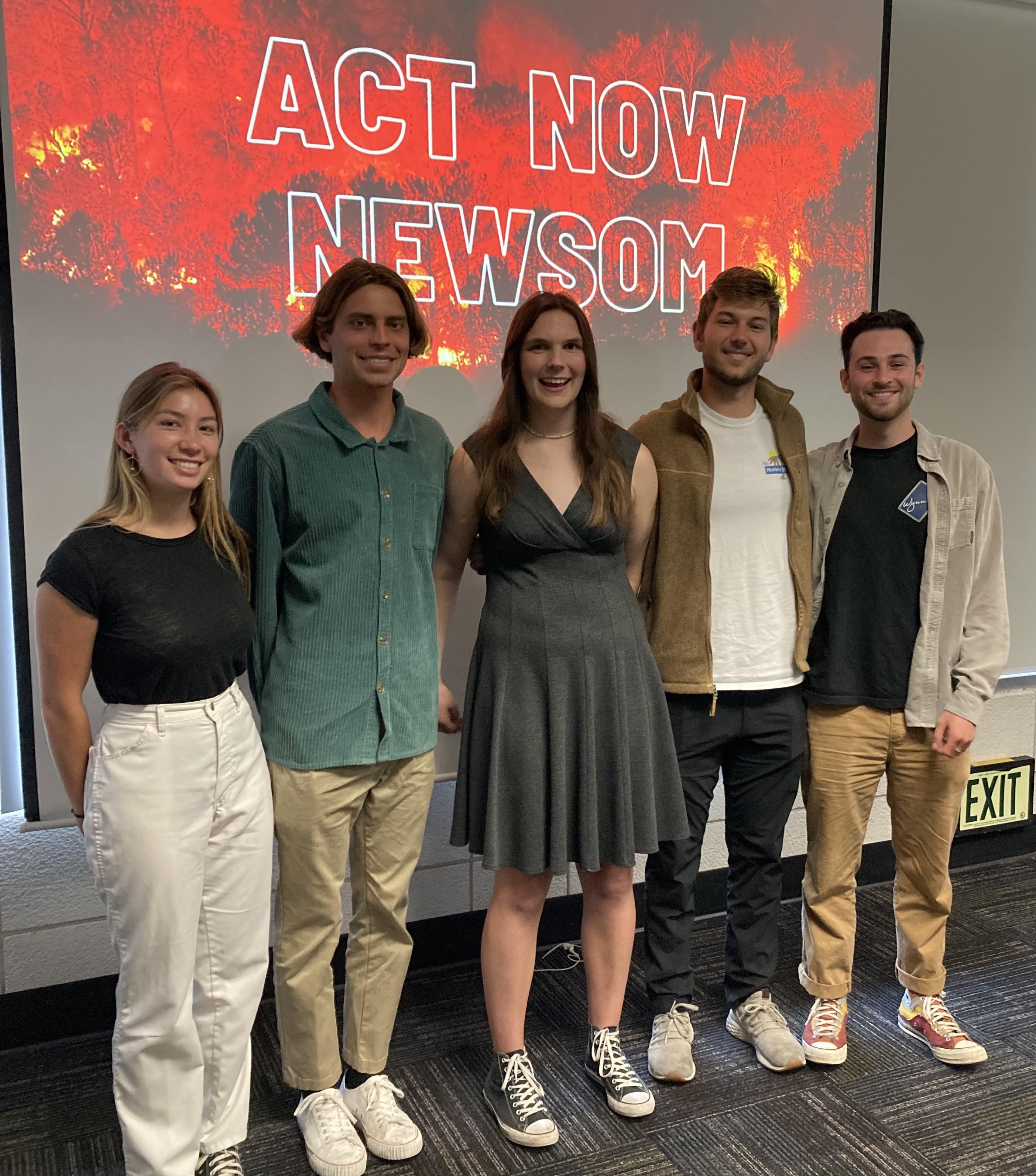 Four ELI Students Stand in Front of "Act Now Newsom"